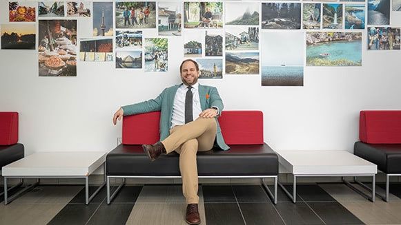 Professor Nacke sitting on a couch in front of a photo wall.