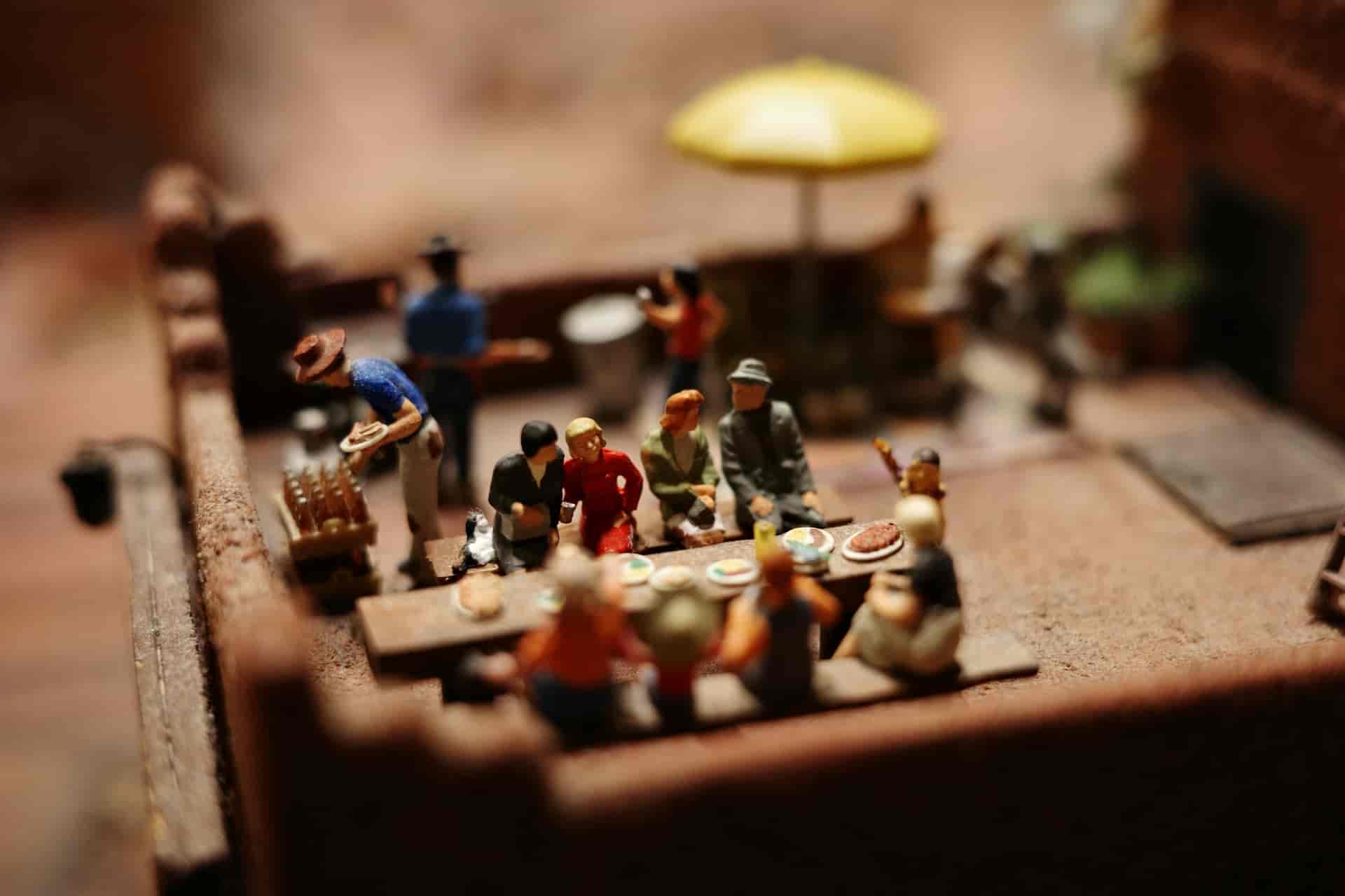 Figuritas de varios personajes sentados en una gran mesa de una posada comiendo