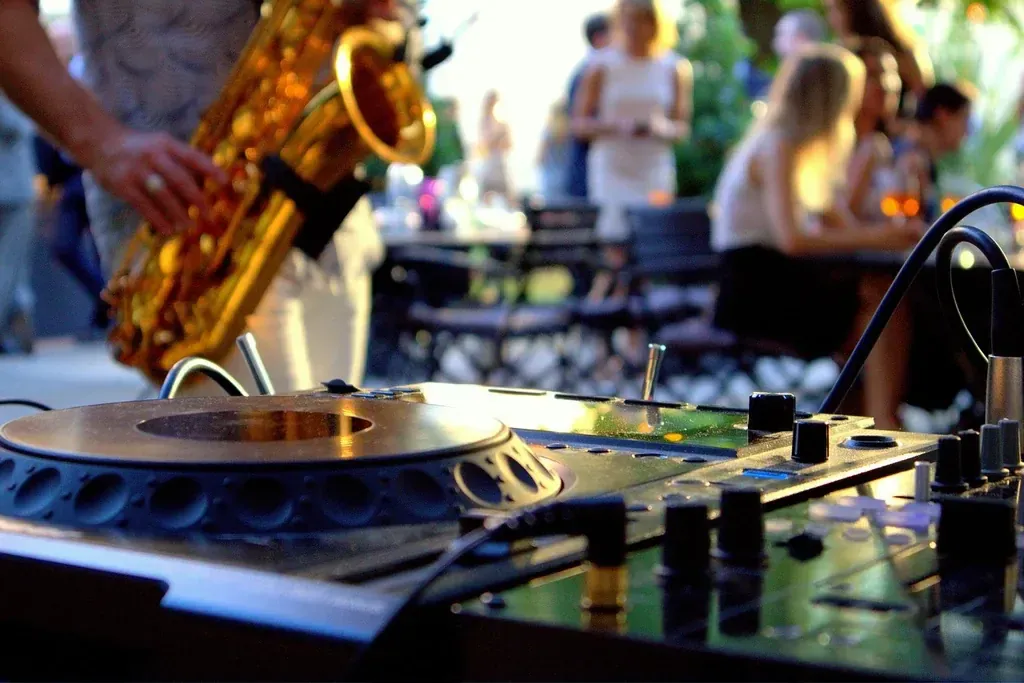 DJ-controller op de voorgrond, saxofonist daarachter