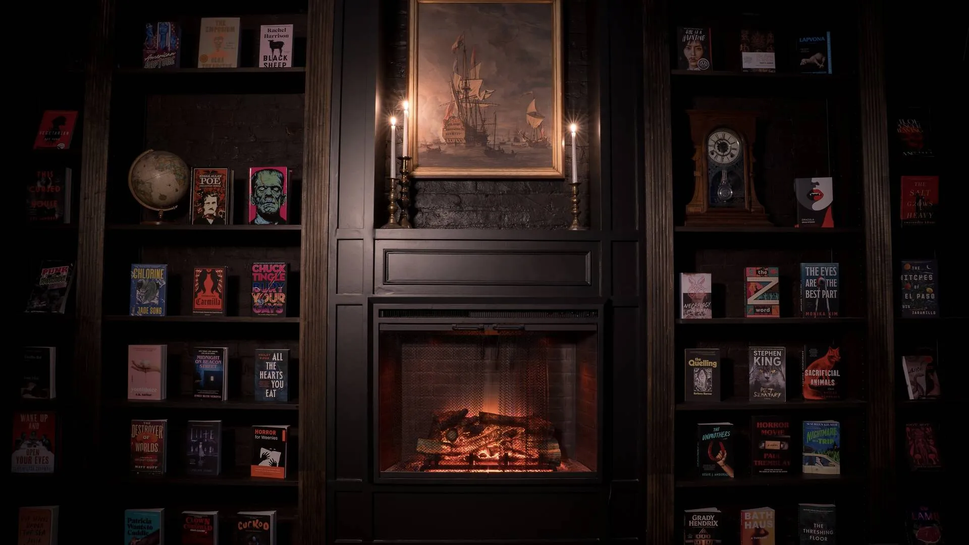 A fireplace surrounded by dark wood bookshelves with a painting of a ship above it.