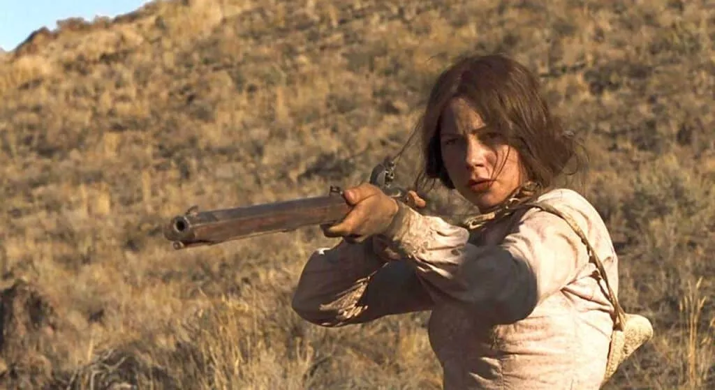Still from Meek's Cutoff: Emily (Michelle Williams) stands pointing a rifle