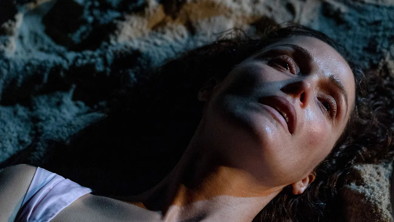 Still from If I Had Legs I'd Kick You: Linda (Rose Byrne) lies on the sand at night