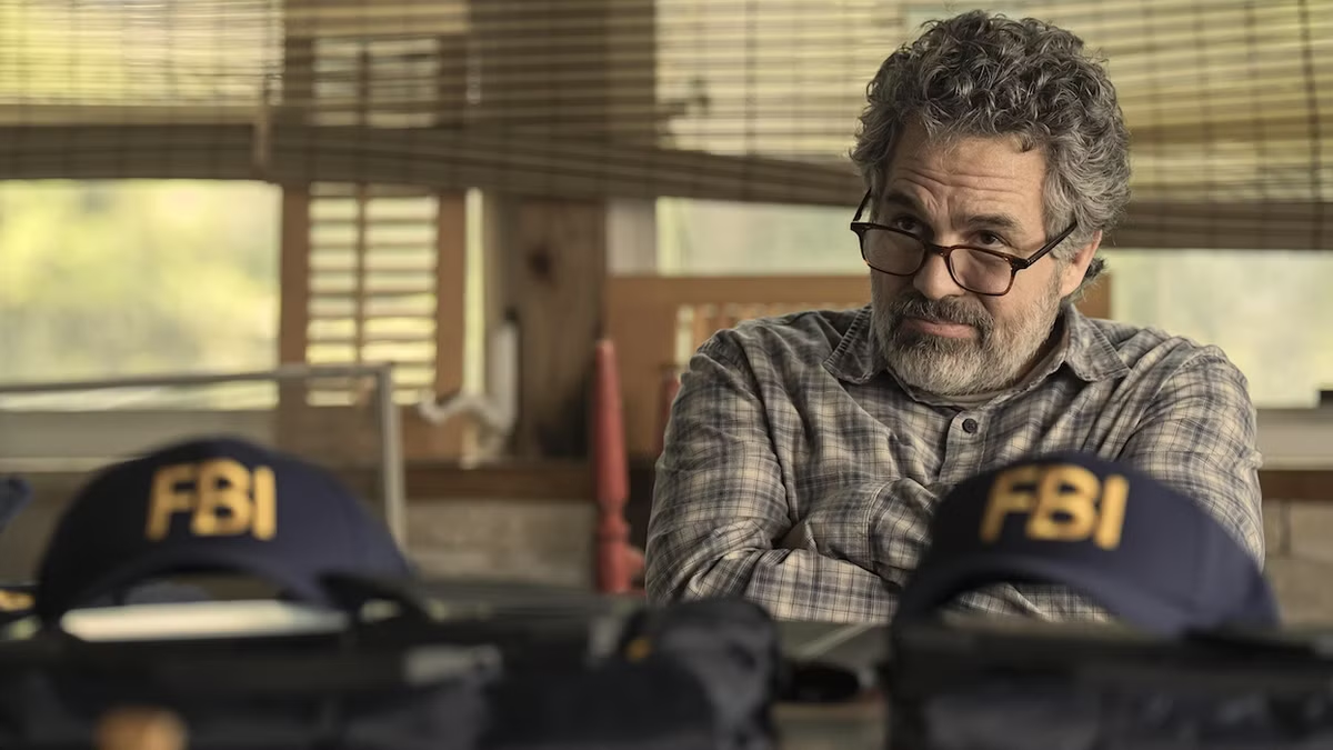 Still from Task: Tom Brandis (Mark Ruffalo) sits behind a desk with two FBI hats on it