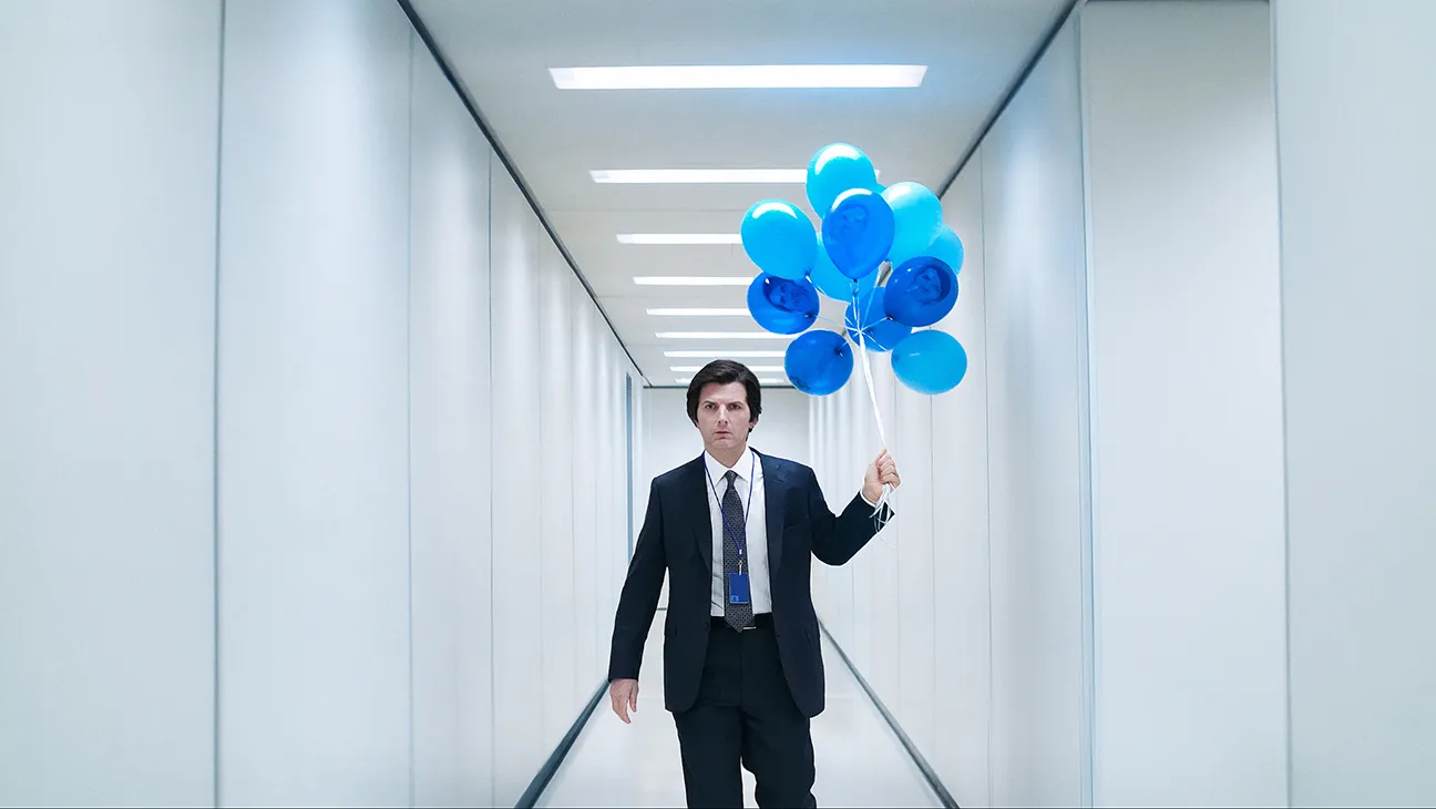 Still from Severance: Mark (Adam Scott) walks down a hallway with blue balloons