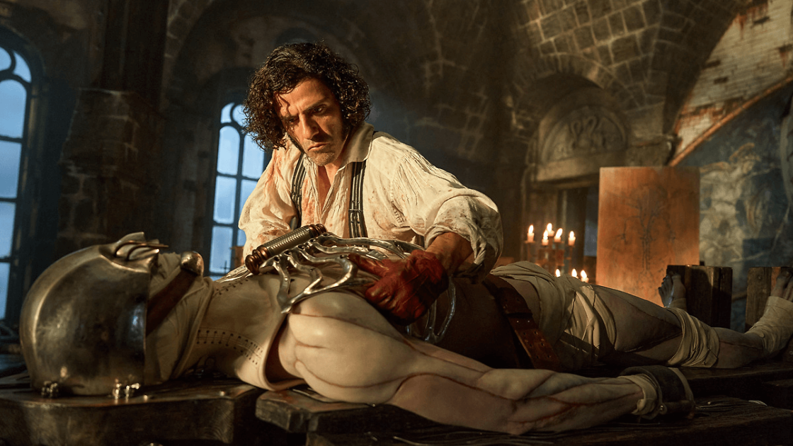 Still from Frankenstein: Victor Frankenstein (Oscar Isaac) puts a metal ribcage on a corpse