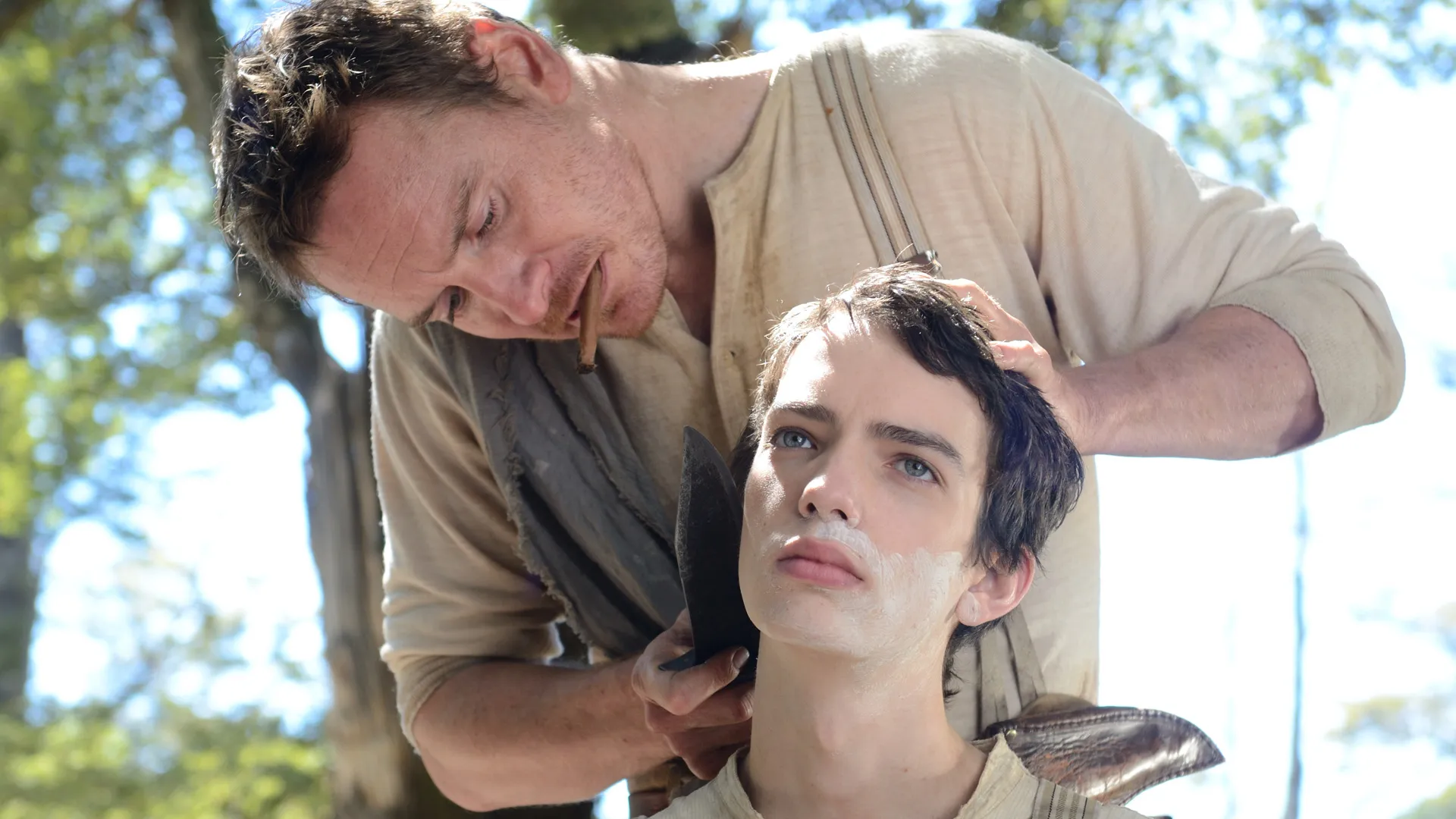 Still from Slow West: Silas (Michael Fassbender) shaves Jay (Codi Smit-McPhee) while smoking a cigarette