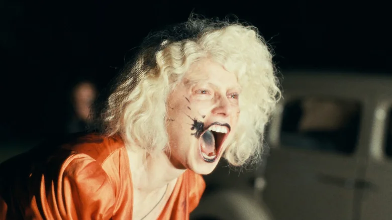 The Bride! (Jessie Buckley) stands screaming at night, lit up by headlights