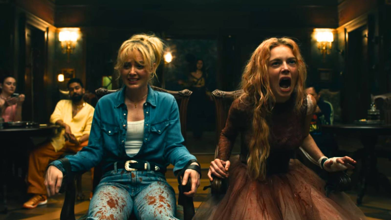 Still image from the film Ready Or Not 2: Here I Come: sisters Grace (Samara Weaving) and Faith (Kathryn Newton) sit tied up next to each other. They are both covered in blood and Grace is screaming