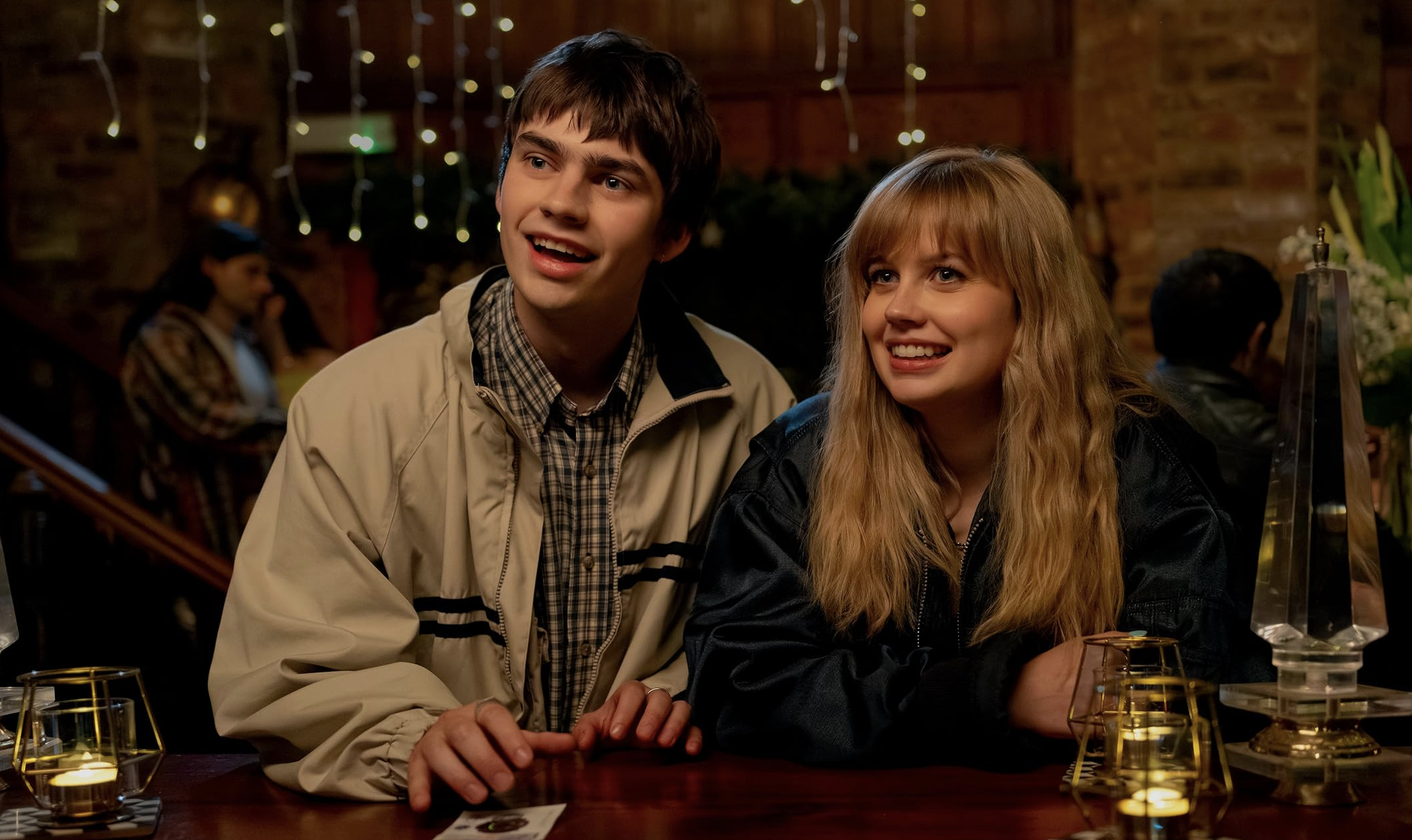 Still from Finding Emily: Owen and Emily lean up against a bar together, looking up expectantly