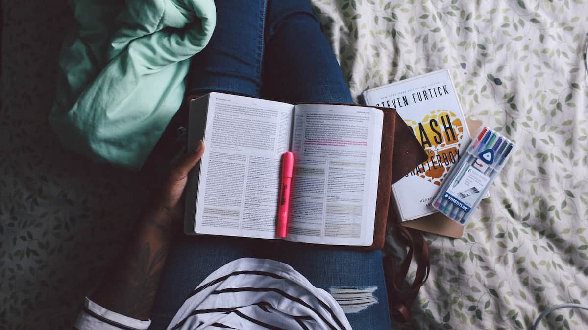 Open Bible in lap of woman. Highlighters and pens available.