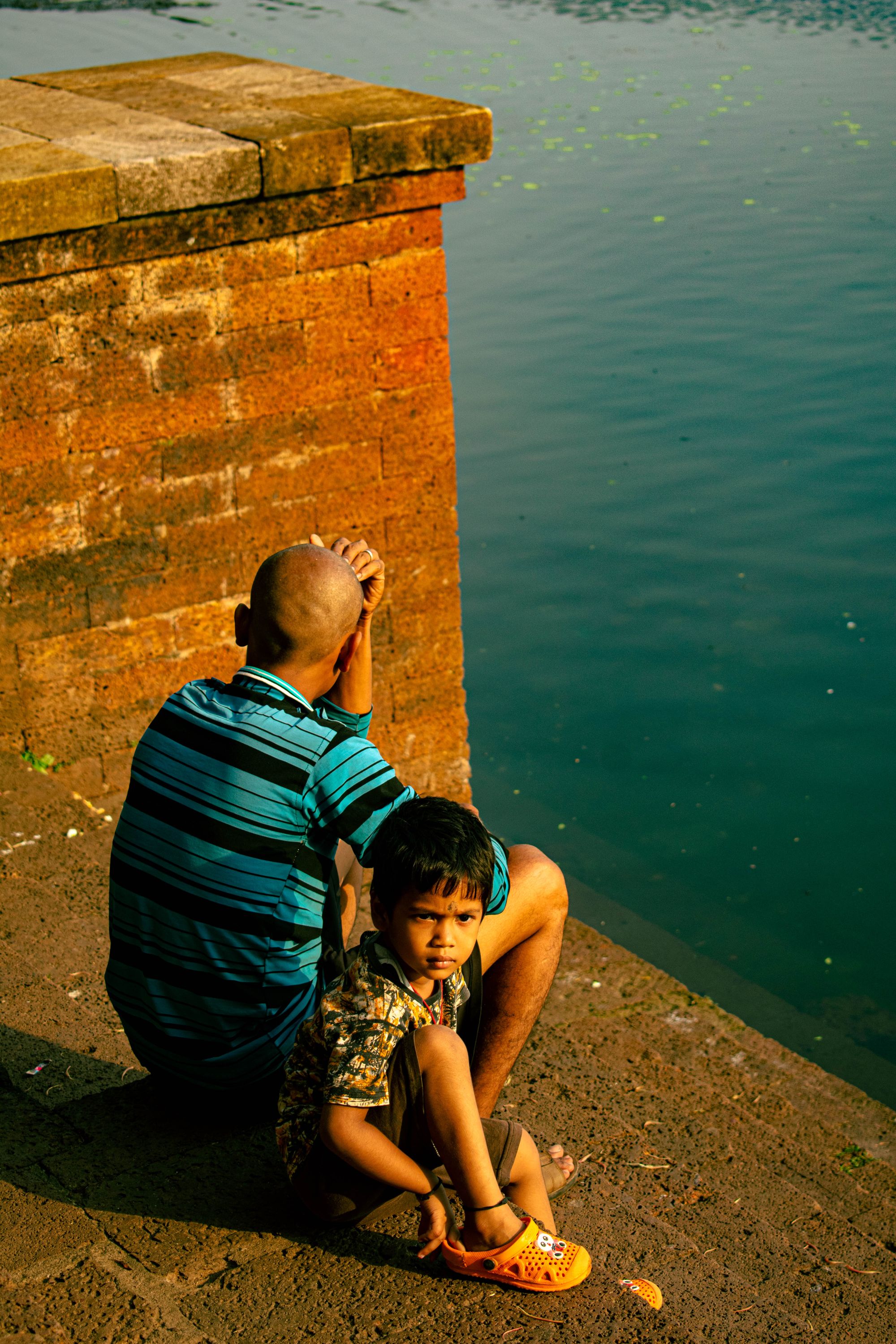 Dad and Son sitting at a Lake in the Morning