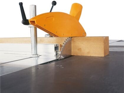 Detaliu cu pânza fierăstrăului circular SCM Minimax tăind o bucată de lemn masiv, cu apărătoarea de siguranță montată.