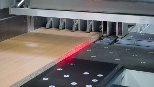 Detaliu cu sistemul de poziționare cu laser (Laser-Positionierung) și clemele de prindere ale unui fierăstrău HOLZ-HER ZENTREX, aliniind un panou de PAL.