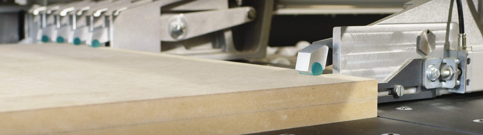 Detaliu cu clemele de prindere (Plattenklemmen) ale unui fierăstrău de debitat HOLZ-HER, aliniind un pachet de panouri de MDF/PAL pentru tăiere.