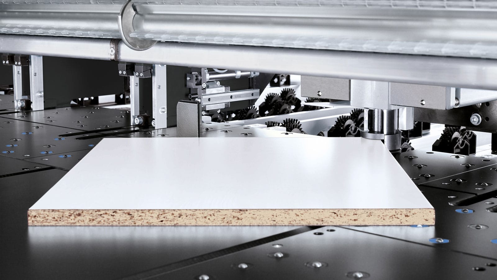 Detaliu cu dispozitivul automat de tăiere în unghi (automatic angle cut device) al unui fierăstrău de debitat HOMAG, poziționând un panou de PAL melaminat pe masa cu perne de aer.