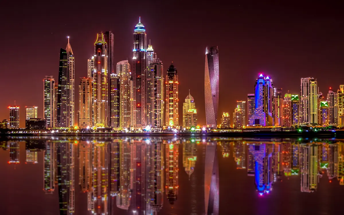 "Dubai skyline illuminated at night, showcasing towering skyscrapers and dazzling city lights."